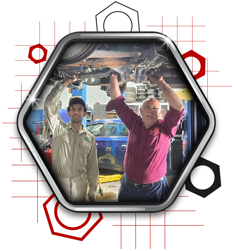 Ethan and Sam inspecting the exhaust system of a car on the hoist.